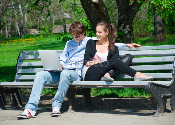 Молодая пара вместе работает на ноутбуке в парке