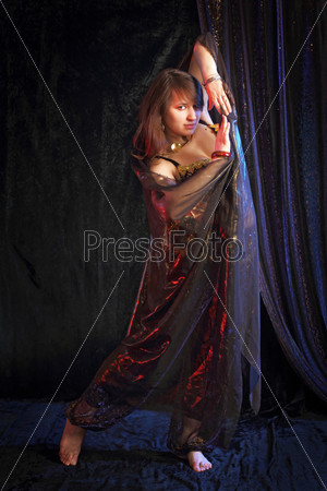 The beautiful girl the brunette executes an oriental dance with a transparent fabric