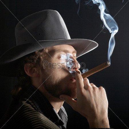 A young bearded man with cigar in a grey hat