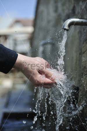 Clear fresh mountain water falling on hands outdoor in nature, stock photo