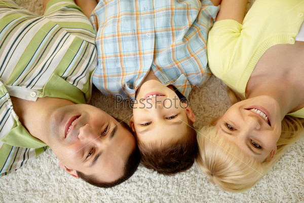Overview of a happy family lying on the carpet