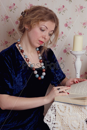 Girl reading book with candle, stock photo