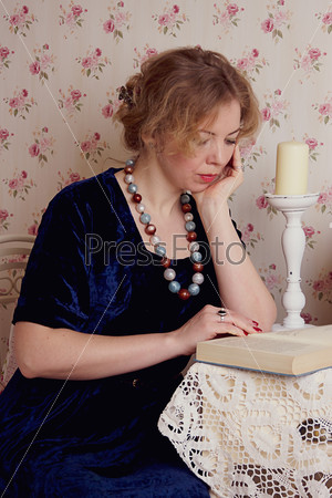 Girl reading book with candle, stock photo