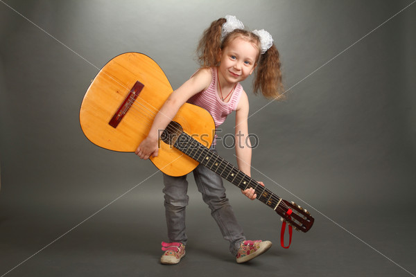 the little girl costs with a big guitar, a look in a lens, a guitar holds for a signature stamp, a horizontal shot, a double 1