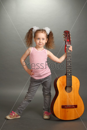 the little girl costs with a big guitar, a look not in a lens, the guitar is held for a signature stamp vertically, by a vertical shot, a double 1