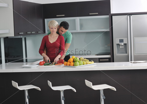 happy young couple have fun in  modern kitchen indoor  while preparing fresh fruits and vegetables food salad