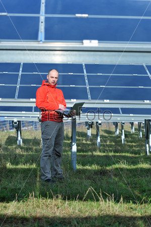 engineer using laptop at solar panels plant field