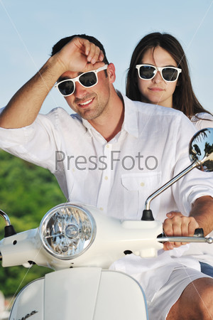 Portrait of happy young love couple on scooter enjoying themselves in a park at summer time, stock photo