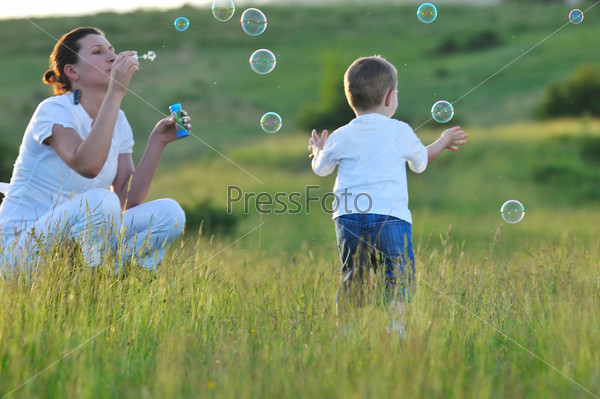 Счастливая молодая мать играет с маленьким сыном на природе летним днем