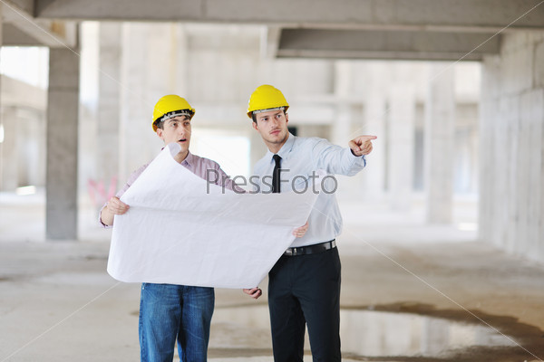 Архитектор и прораб проверяют документы на строительном объекте