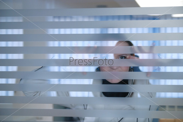 young businesswoman looking through transparent wall