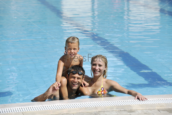 Счастливая семья в плавательном бассейне на открытом воздухе