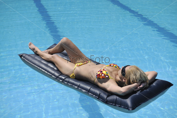 Девушка в бассейне на надувном матрасе