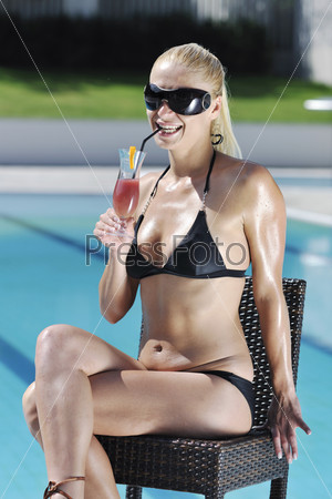 young beautiful woman relax drink coctail and have fun with splashing water at hotel swimming pool