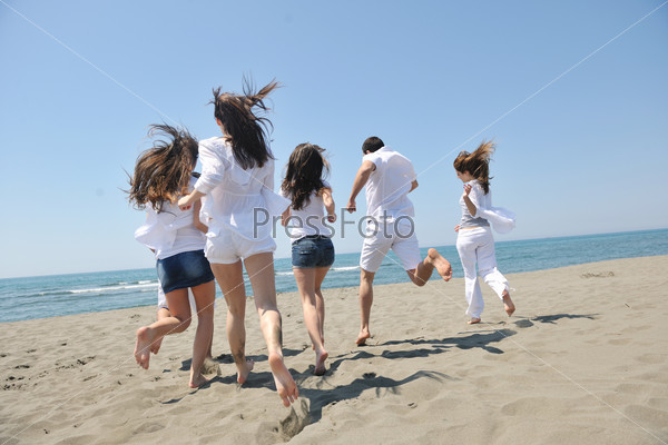 Группа отдыхающих, бегущая к морю по песчаному пляжу