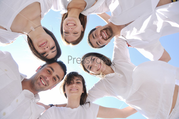 Group of happy young people in circle at beach have fun and smile, stock photo