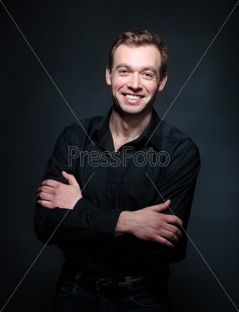 Handsome smiling man in black against the black background