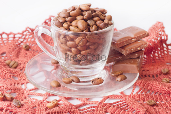 Чашка с кофейными зернами, шоколад и салфетка на светлом фоне