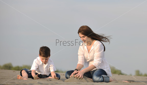 happy young mother  and son relaxing and play ind sand games on beach at summer season