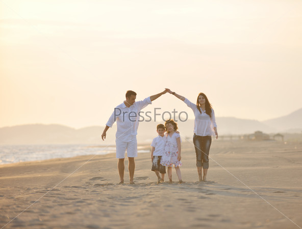 Happy young family have fun on beach run and jump at sunset, stock photo