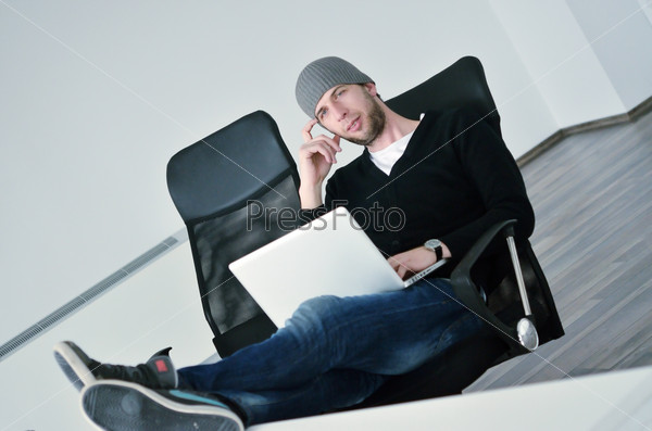 Casual young business man relax and work on laptop computer with foots on table, stock photo