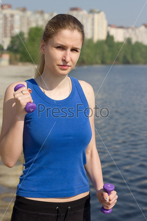 Young woman with weights exercising in the nature