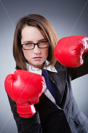 Молодая деловая женщина в красных боксерских перчатках на сером фоне