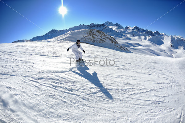 skier skiing downhill on fresh powder snow  with sun and mountains in background