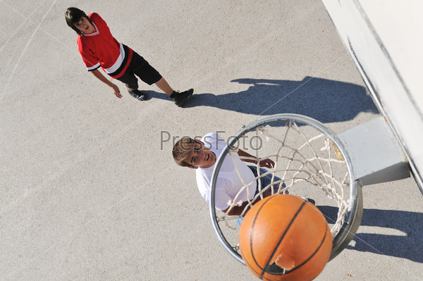 group of young boys who playing basketball outdoor on street with long shadows and bird view perspective
