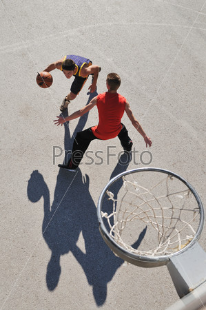 group of young boys who playing basketball outdoor on street with long shadows and bird view perspective