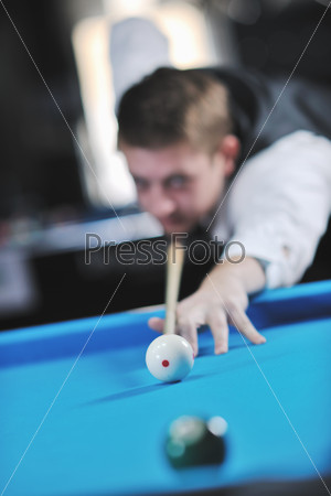 Молодой мужчина играет в бильярд