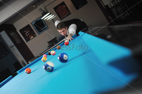 Young pro billiard player finding best solution and right angle at billard or snooker pool sport game , stock photo