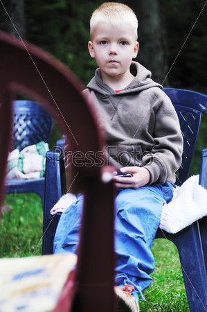 Мальчик сидит в кресле с телефоном на открытом воздухе