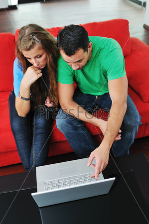 happy young couple have fun and relax at comfort bright apartment and work on laptop computer happy young couple have fun and relax at comfort bright apartment and work on laptop computer