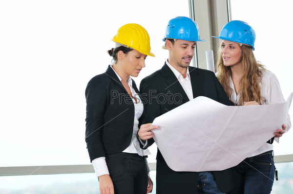 young architect group in big bright modern new apartment looking blueprints and building plans