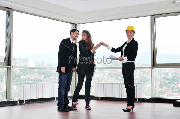happy young couple buying new home with real estate agent and  looking big comfort bright apartment plans and taking key