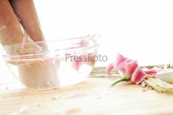 Женские ноги в миске с водой и лепестками