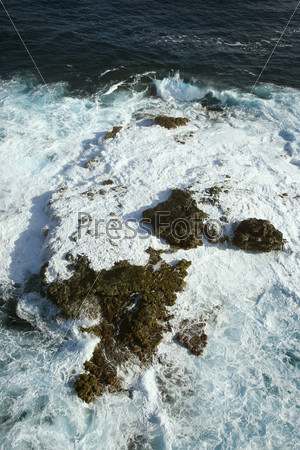 Aerial view of rocks in Pacific ocean with water swirling around them off the coast of Maui, Hawaii.