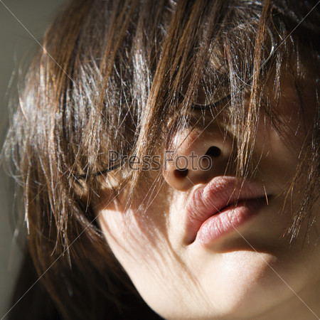 Close up of pretty Asian young woman with hair covering eyes.