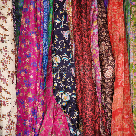 Colorful Mexican patterned fabric hanging on a rack. Square shot.
