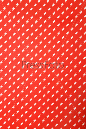 Close-up of vibrant red vintage fabric with repetitive white designs.