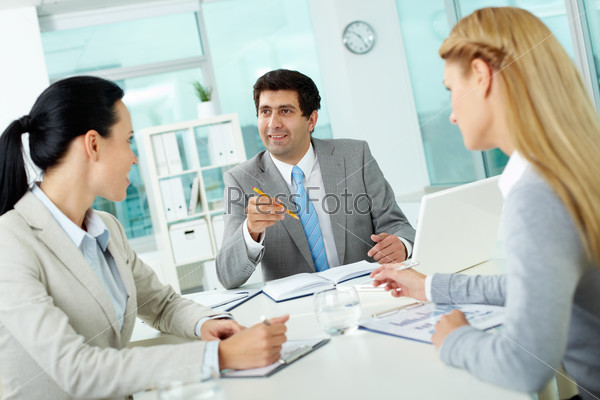 Confident businessman explaining his ideas to employees at meeting