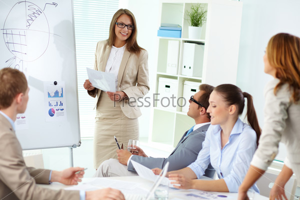 Confident top manager standing by the whiteboard and making report at meeting