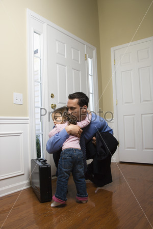 Caucasian businessman   at door with briefcase hugging daughter.