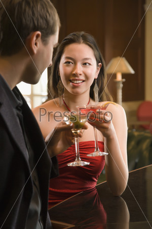 Taiwanese mid adult woman and Caucasian man toasting martinis.