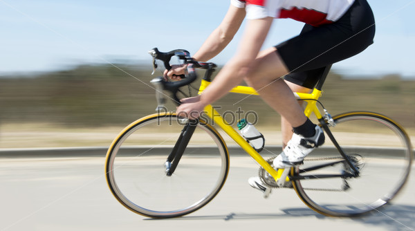 Cyclist on a racing bike speeding past on the verge of a road