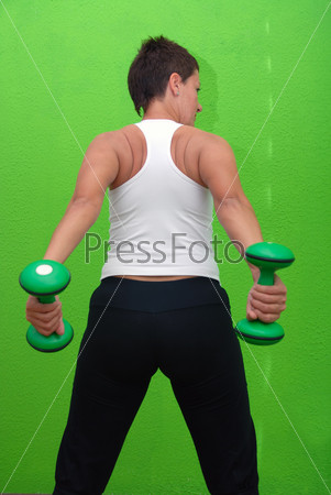 young girl working out with weights in fitness club