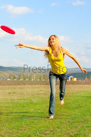 Young woman playing with disc outdoors. Summer\'s games
