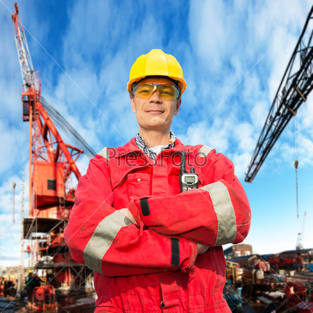 Offshore engineer, looking proudly, standing on the deck of an industrial vessel at the docks