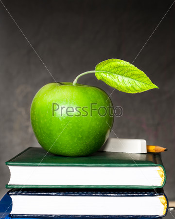 Apple, chalk and pencil on textbooks against blackboard with text \